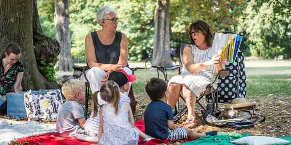 Voorlezers van leeslekker lezen voor aan kinderen in het park.